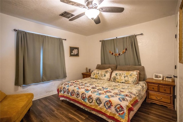 bedroom featuring dark wood-type flooring, visible vents, a textured ceiling, and a ceiling fan