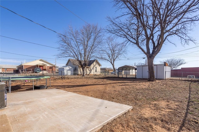 view of yard with a carport, a trampoline, and fence