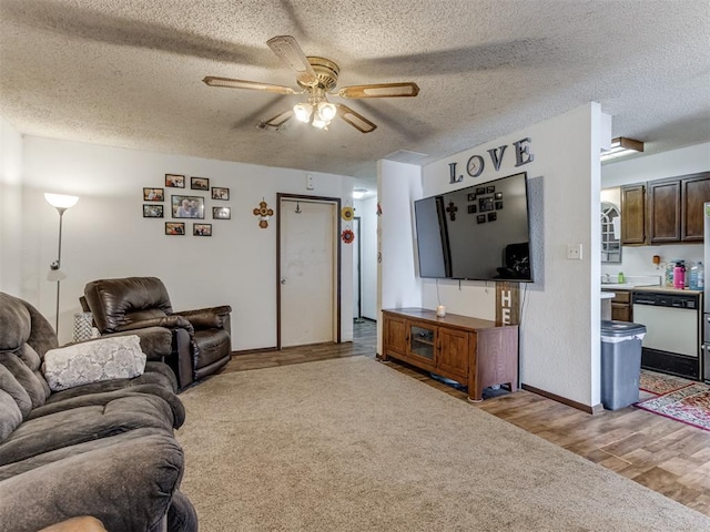 carpeted living room featuring ceiling fan, a textured ceiling, baseboards, and wood finished floors