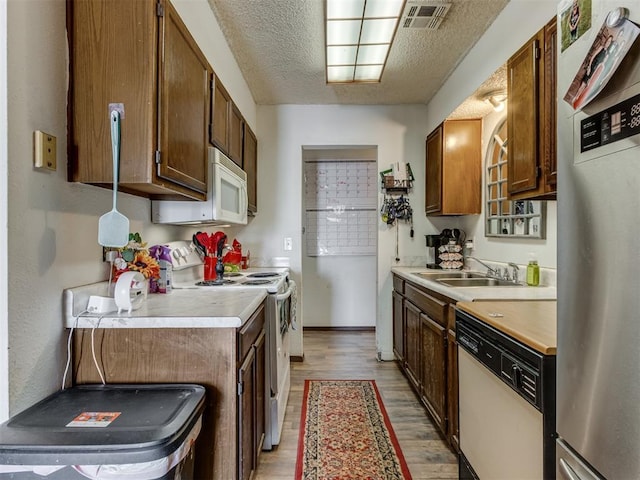 kitchen with white appliances, light wood finished floors, visible vents, light countertops, and a textured ceiling