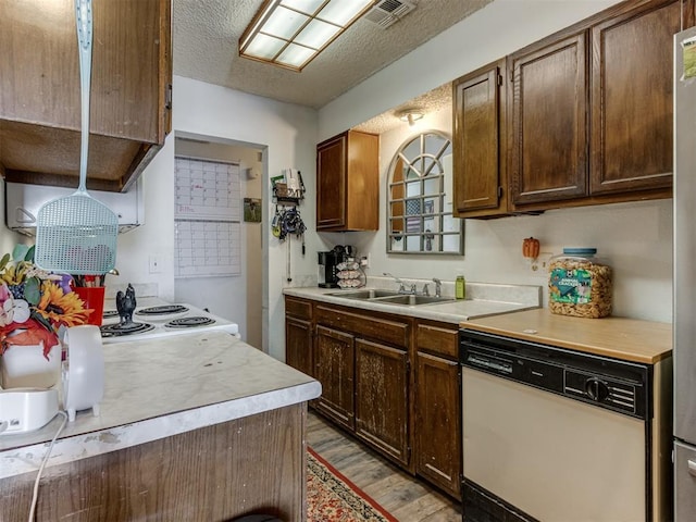 kitchen with white dishwasher, stove, light countertops, and a sink