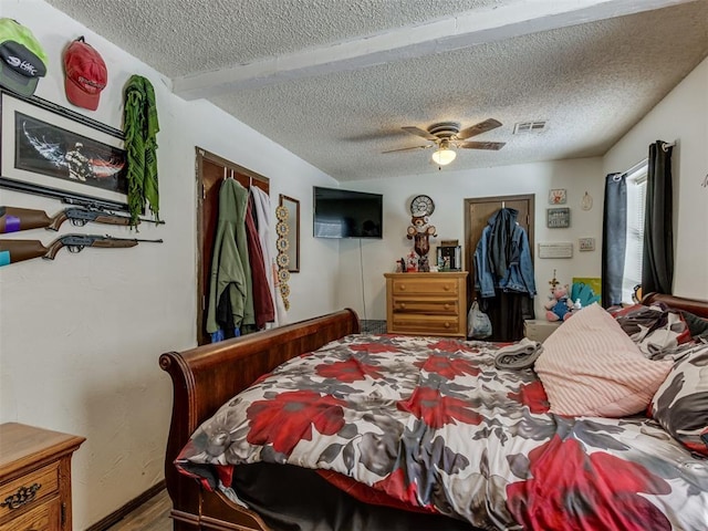 bedroom featuring a textured ceiling, wood finished floors, visible vents, a ceiling fan, and a closet