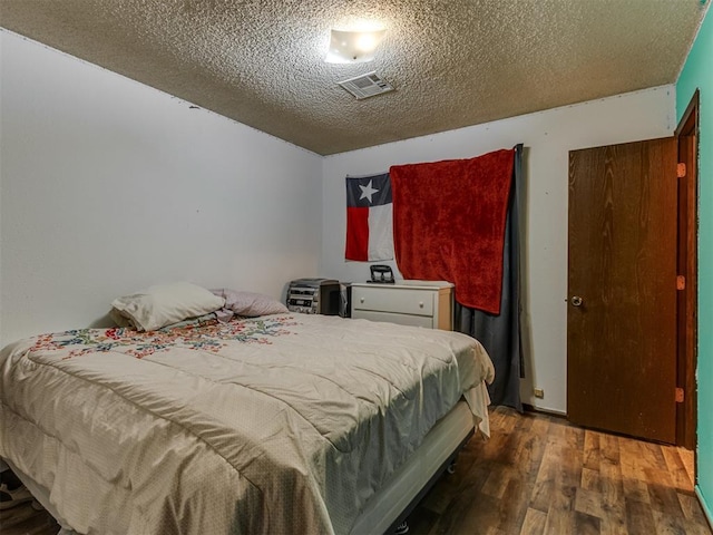 bedroom with a textured ceiling, visible vents, and dark wood-type flooring