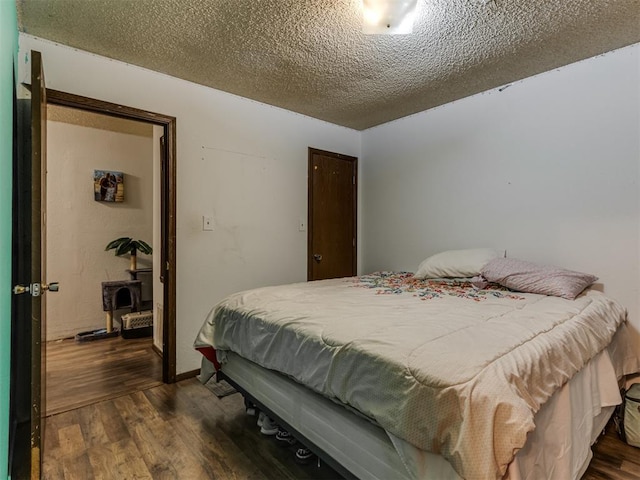 bedroom with a closet, a textured ceiling, and dark wood-style flooring