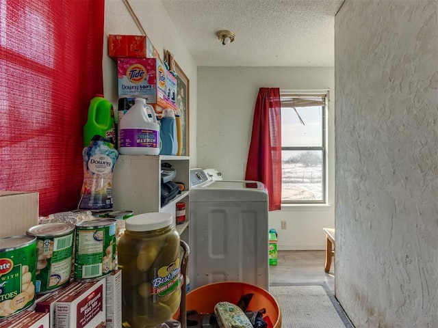 washroom featuring laundry area, washer / clothes dryer, a textured ceiling, and a textured wall