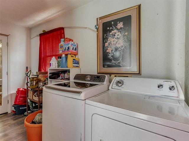 laundry area with laundry area, washer and clothes dryer, and wood finished floors