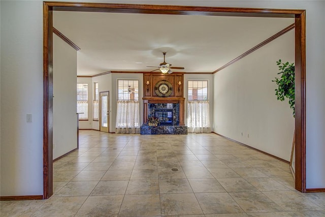 unfurnished living room with ornamental molding, a premium fireplace, plenty of natural light, and a ceiling fan