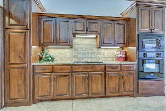 kitchen with black appliances, light stone counters, light tile patterned flooring, and tasteful backsplash