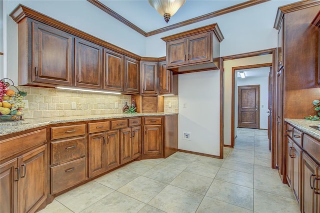 kitchen with light tile patterned floors, baseboards, light stone counters, crown molding, and backsplash