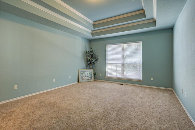 carpeted empty room with baseboards, a raised ceiling, visible vents, and crown molding