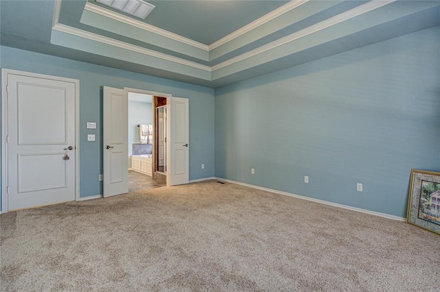 carpeted spare room with baseboards, ornamental molding, and a raised ceiling