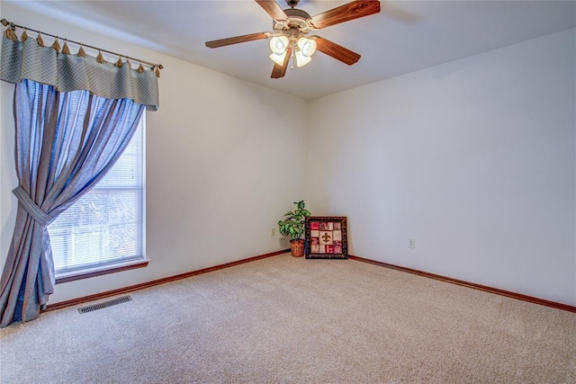 carpeted empty room with baseboards, visible vents, and a ceiling fan