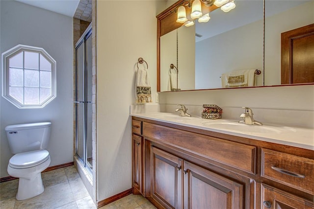 bathroom featuring double vanity, a stall shower, a sink, and toilet