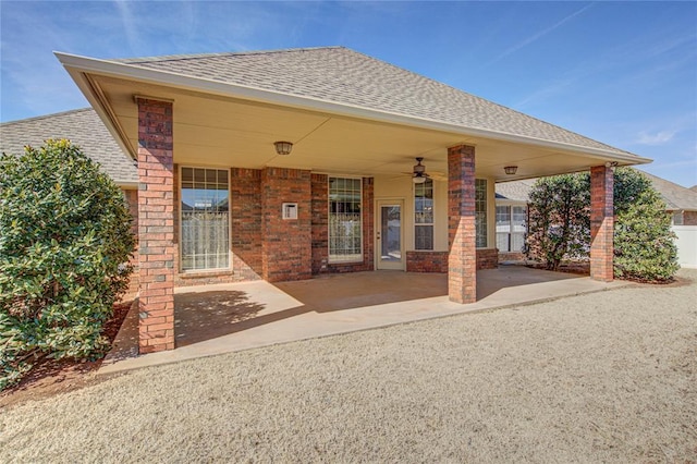 rear view of house featuring a patio area, roof with shingles, ceiling fan, and brick siding