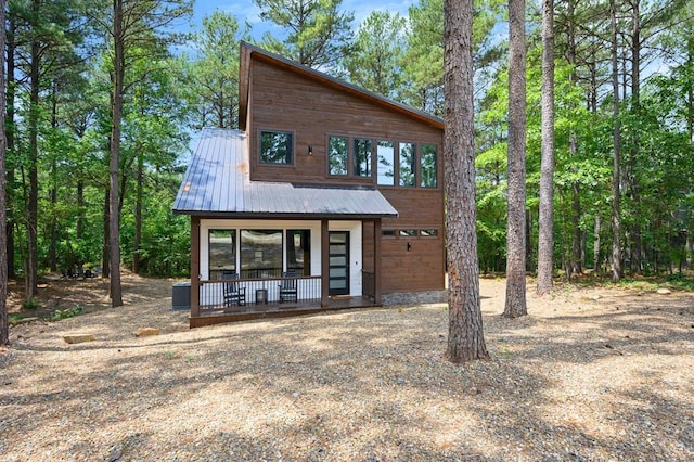 modern home with metal roof, driveway, and a porch