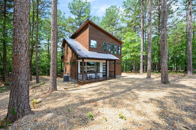 rear view of property featuring central air condition unit, a porch, and metal roof