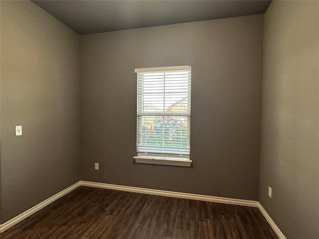 unfurnished room with baseboards and dark wood-type flooring