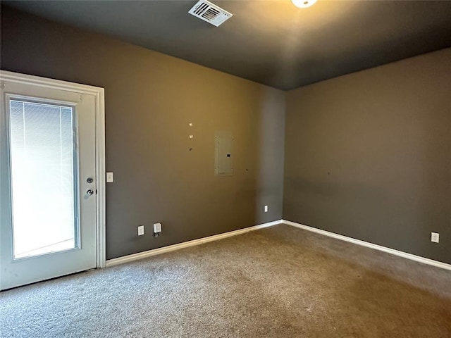 unfurnished room featuring carpet floors, electric panel, visible vents, and baseboards