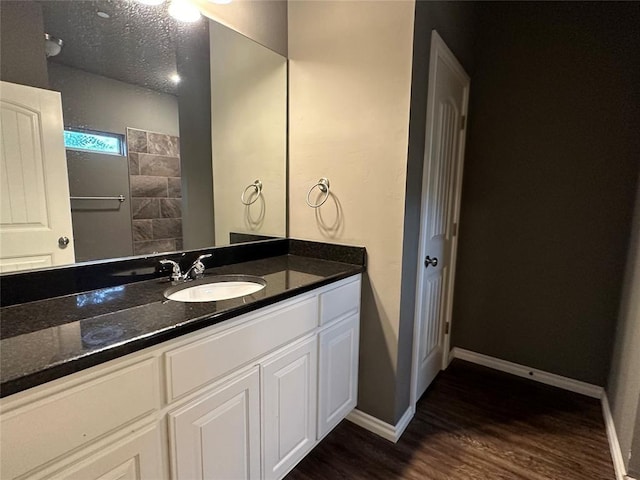 bathroom featuring baseboards, vanity, a textured ceiling, and wood finished floors