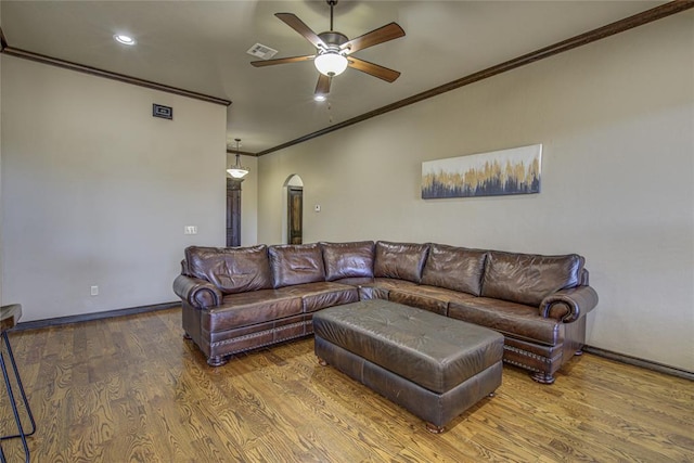 living area with arched walkways, visible vents, ornamental molding, a ceiling fan, and wood finished floors