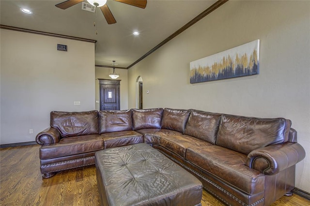 living room featuring visible vents, arched walkways, wood finished floors, and ornamental molding