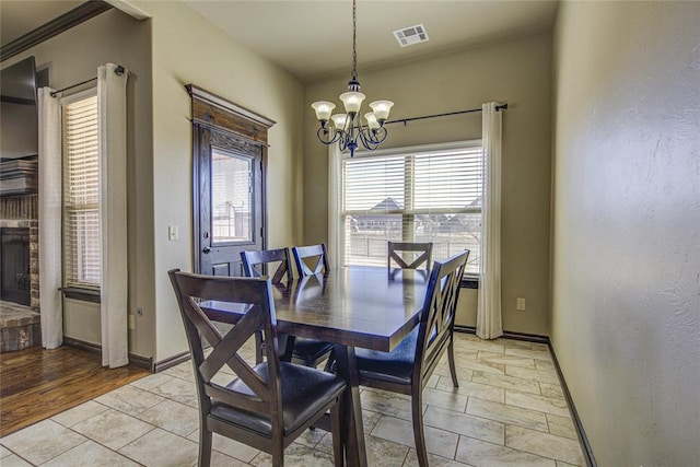 dining area featuring a healthy amount of sunlight, visible vents, a notable chandelier, and baseboards