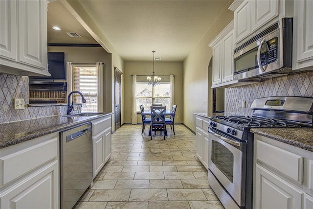 kitchen featuring stainless steel appliances, dark stone counters, white cabinets, and a sink