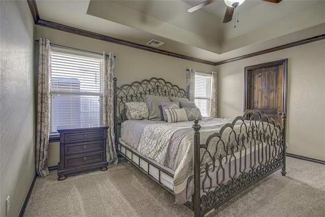 carpeted bedroom featuring visible vents, a tray ceiling, ceiling fan, and ornamental molding