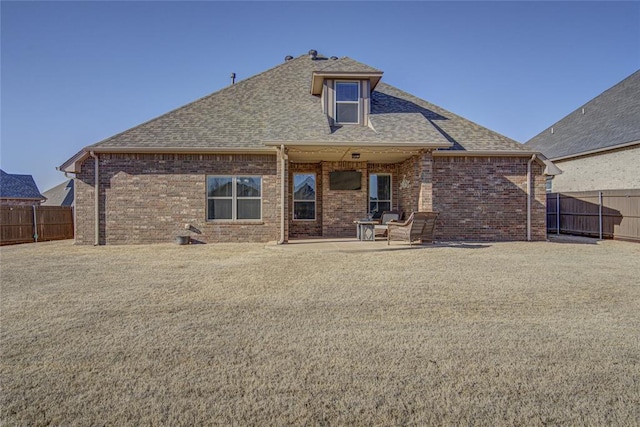 rear view of property with a patio area, a fenced backyard, roof with shingles, and brick siding