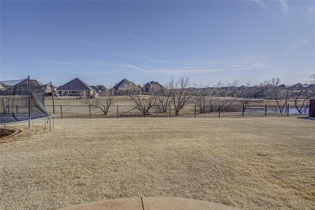 view of yard with a trampoline, a residential view, and a fenced backyard