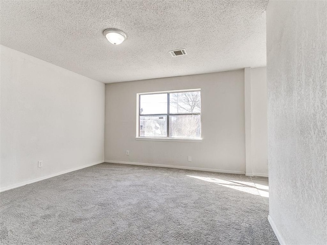 empty room with carpet floors, baseboards, visible vents, and a textured ceiling