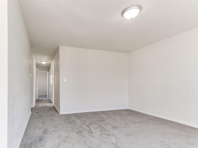 empty room featuring baseboards, a textured ceiling, and light colored carpet