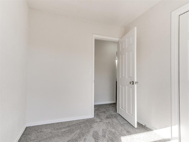 empty room featuring light colored carpet and baseboards