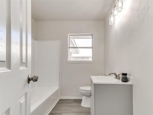 bathroom with toilet, washtub / shower combination, vanity, wood finished floors, and baseboards