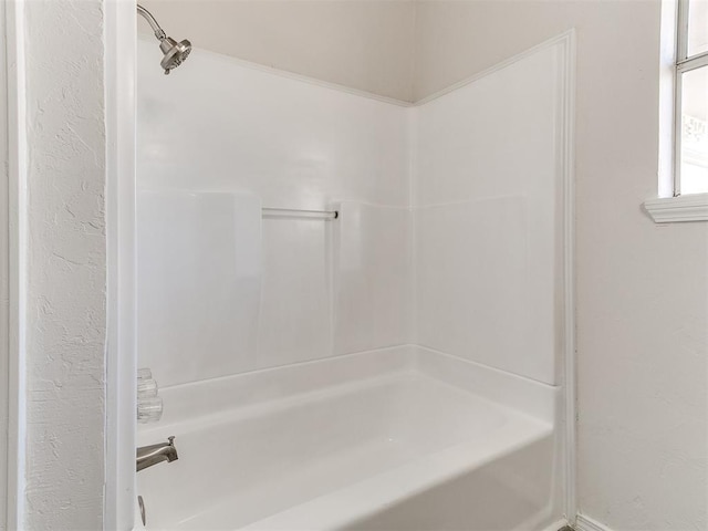 bathroom featuring a textured wall and shower / tub combination