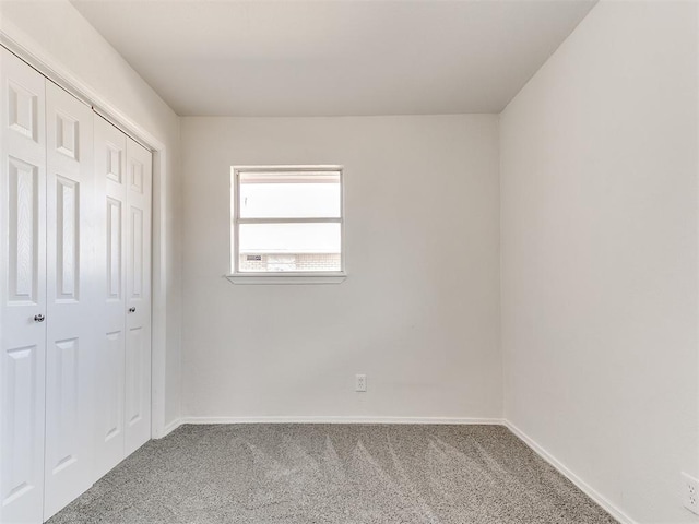 unfurnished bedroom with a closet, baseboards, and carpet flooring