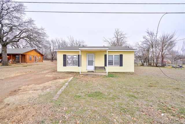 bungalow featuring a front lawn and dirt driveway