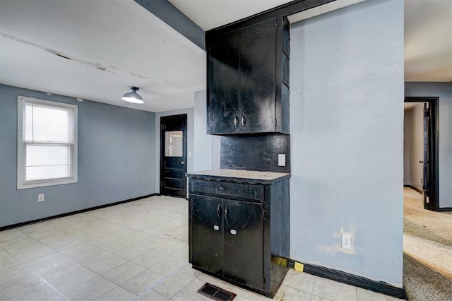 kitchen with baseboards, backsplash, visible vents, and dark cabinets