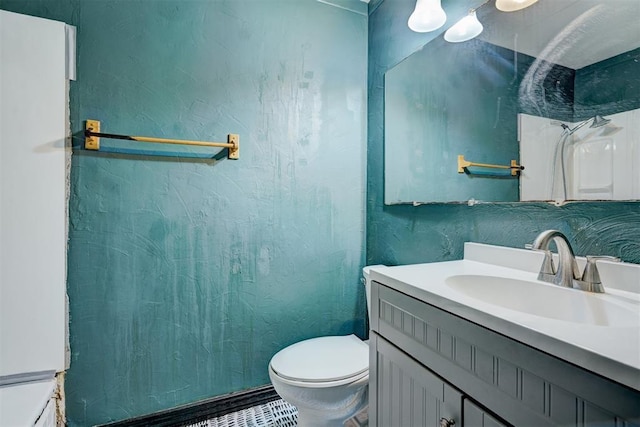 full bath with a textured wall, vanity, and toilet