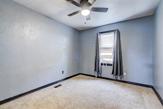 empty room featuring carpet floors, visible vents, a textured wall, a ceiling fan, and baseboards