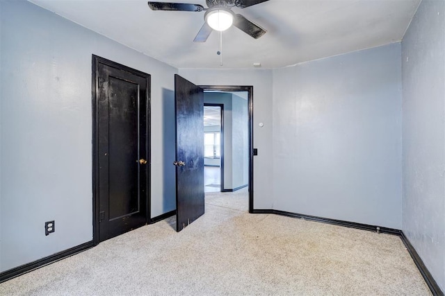 spare room with light carpet, ceiling fan, and baseboards