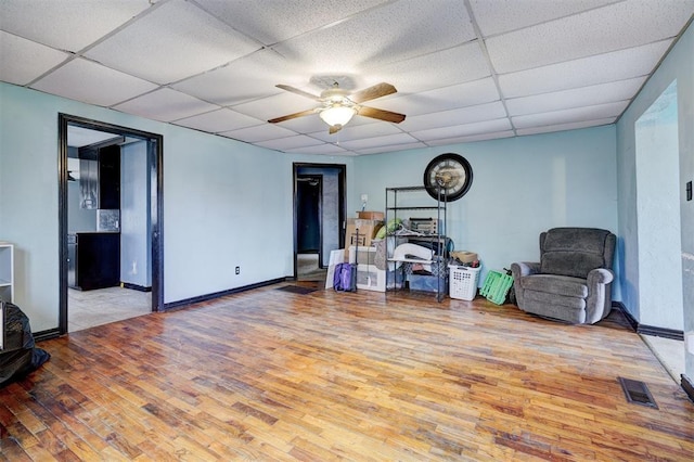 interior space featuring a paneled ceiling, visible vents, light wood-style flooring, and baseboards