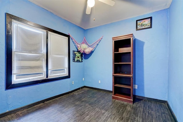 empty room with ceiling fan, baseboards, and wood finished floors