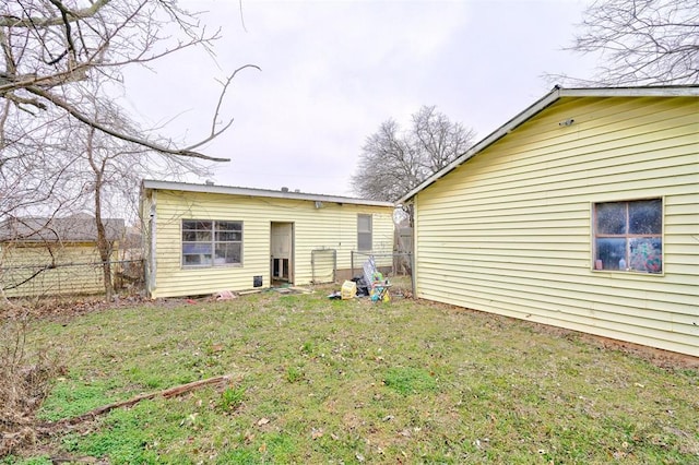 rear view of property with fence and a lawn