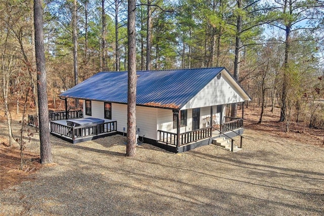 chalet / cabin featuring covered porch, driveway, a deck, and metal roof