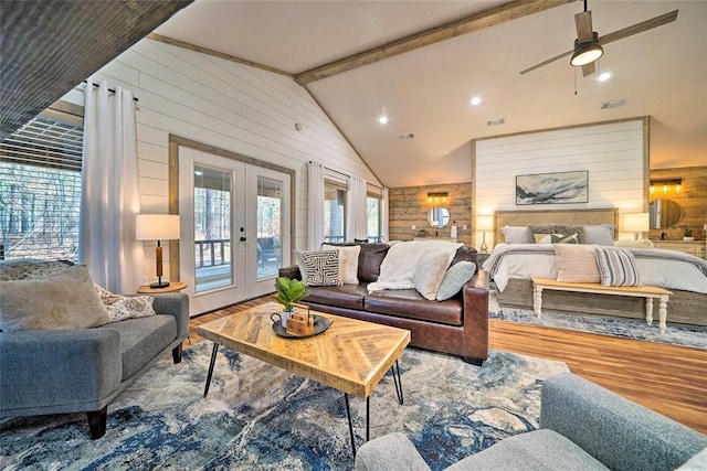 living area featuring lofted ceiling with beams, french doors, wood finished floors, and wooden walls