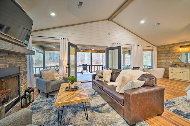 living room featuring vaulted ceiling with beams, a wealth of natural light, wood walls, and visible vents