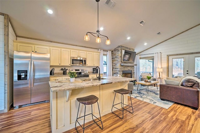 kitchen featuring visible vents, appliances with stainless steel finishes, open floor plan, vaulted ceiling, and light wood-style floors