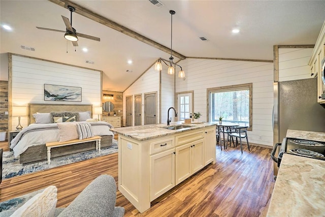 kitchen featuring vaulted ceiling with beams, visible vents, a sink, wooden walls, and wood finished floors