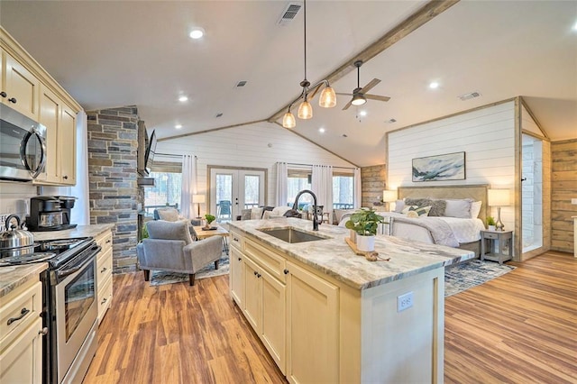 kitchen with stainless steel appliances, open floor plan, a sink, and wooden walls